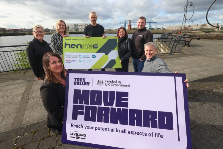 A group of partners from Thirteen, Beyond Housing and Karbon Homes on the quayside with the transporter bridge in the background. They are holding two signs, one that says in partnership with the housing employment network north east and the other with th
