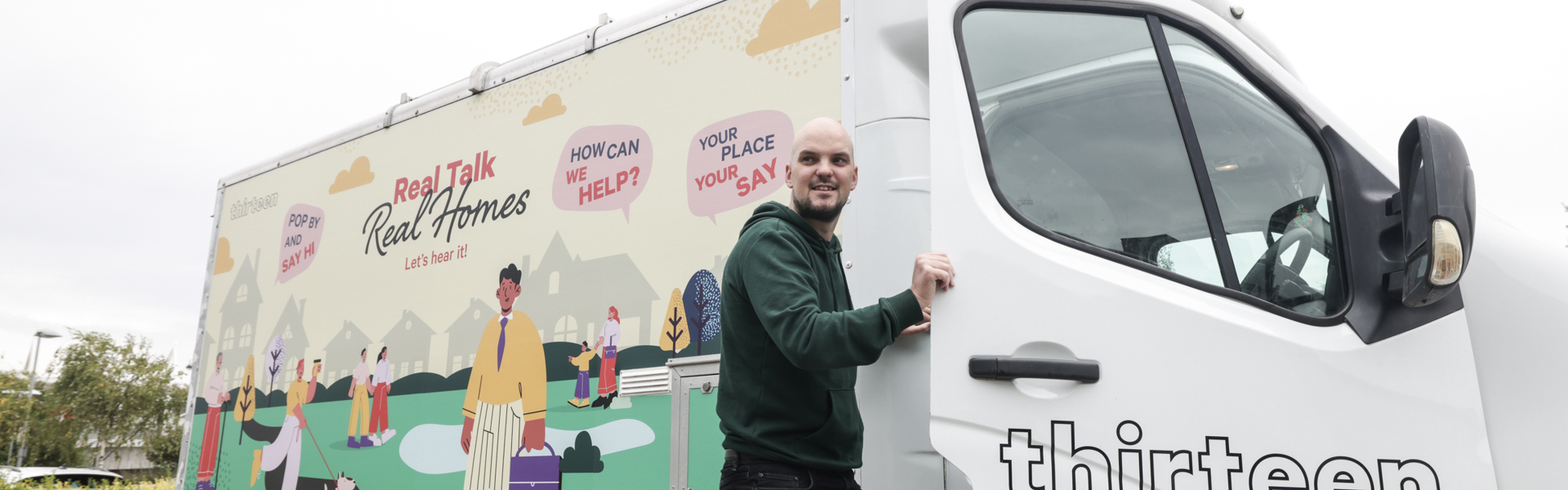 A male stands holding the door open to Thirteen's mobile touchpoint van