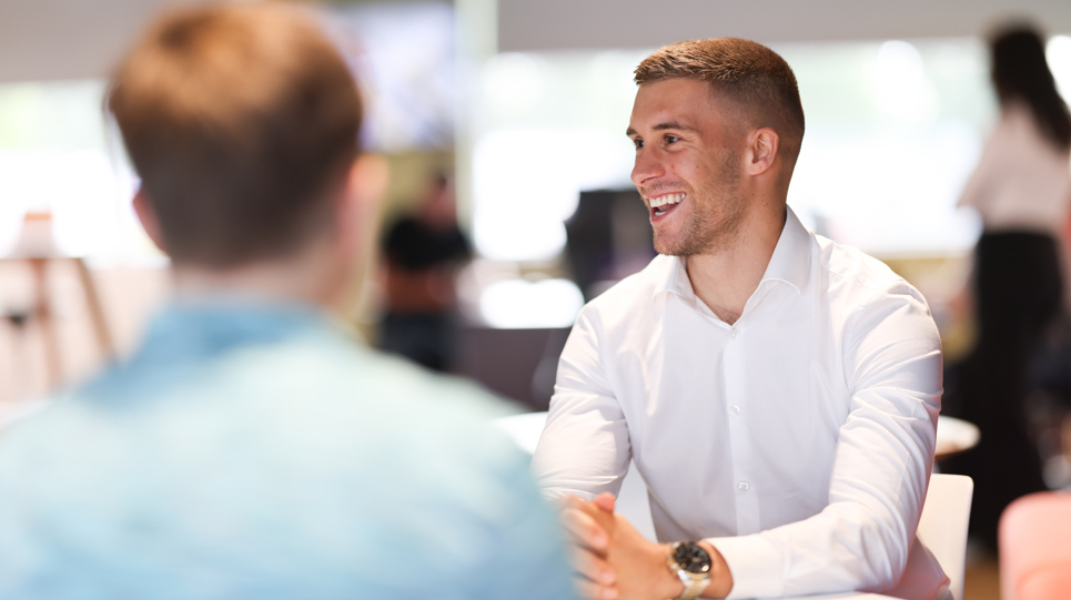 An apprentice smiling and talking to another colleague