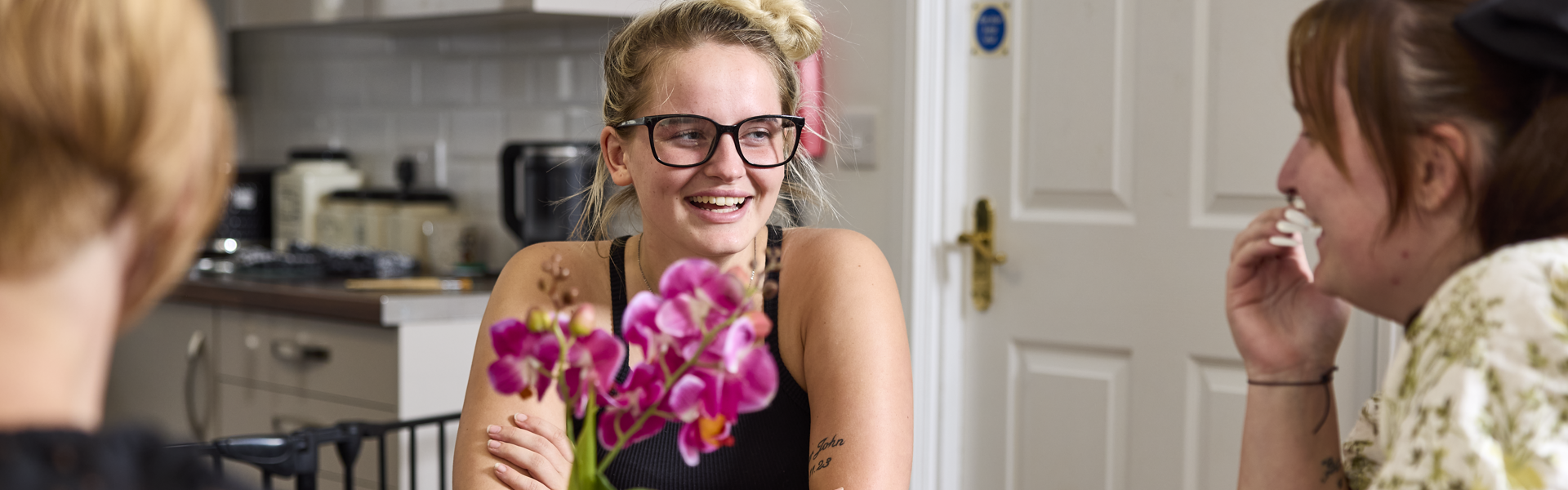 A female customer talking and smiling around a table with two thirteen colleagues at Anna Court.