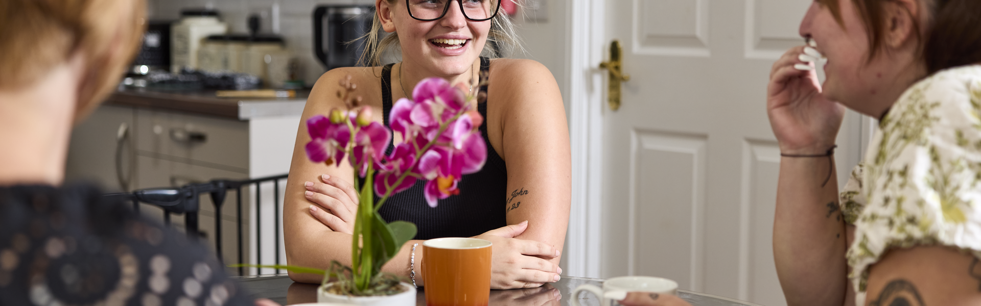 A female customer talking and smiling around a table with two thirteen colleagues at Anna Court.
