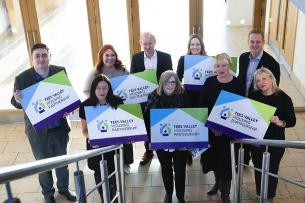 A group of Thirteen colleagues, partners and Chris Cook MP holding Tees Valley Housing Partnership signs.