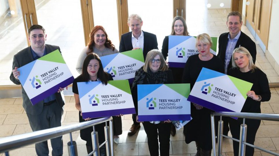 A group of Thirteen colleagues, partners and Chris Cook MP holding Tees Valley Housing Partnership signs.