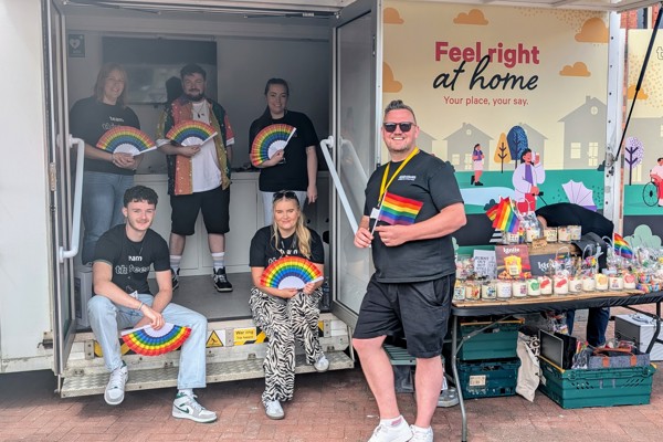 Representatives at Thirteen holding pride fans in front of the mobile touchpoint van