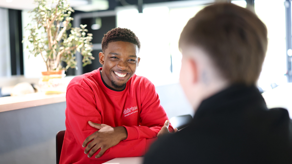 An apprentice smiling and talking to another colleague