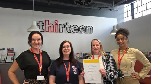 Four members of Thirteen's employability team stand side by side as one holds up a matrix Standard certificate