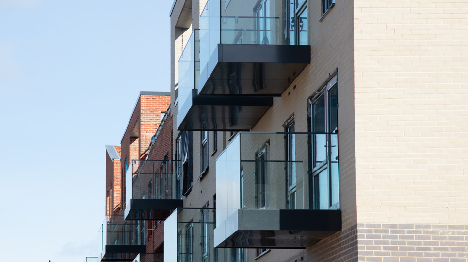A block of modern apartments with glass fronted balconies.