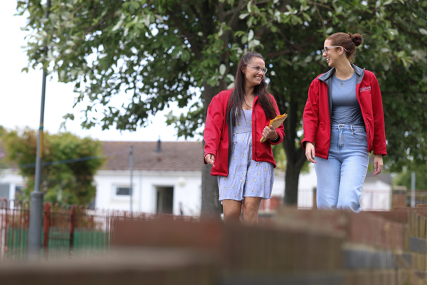 Two housing co-ordinators smiling at each other on estate walkabout 