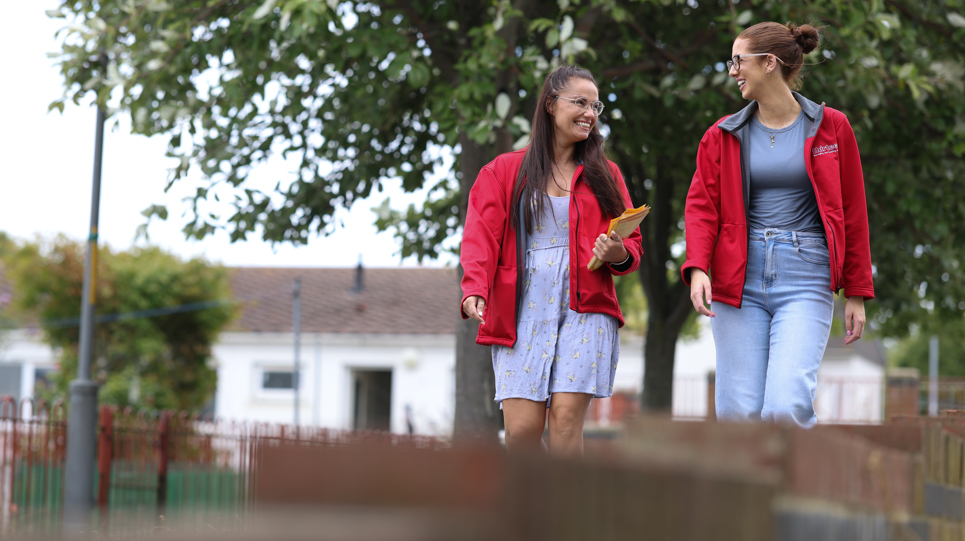 Two housing co-ordinators smiling at each other on estate walkabout 