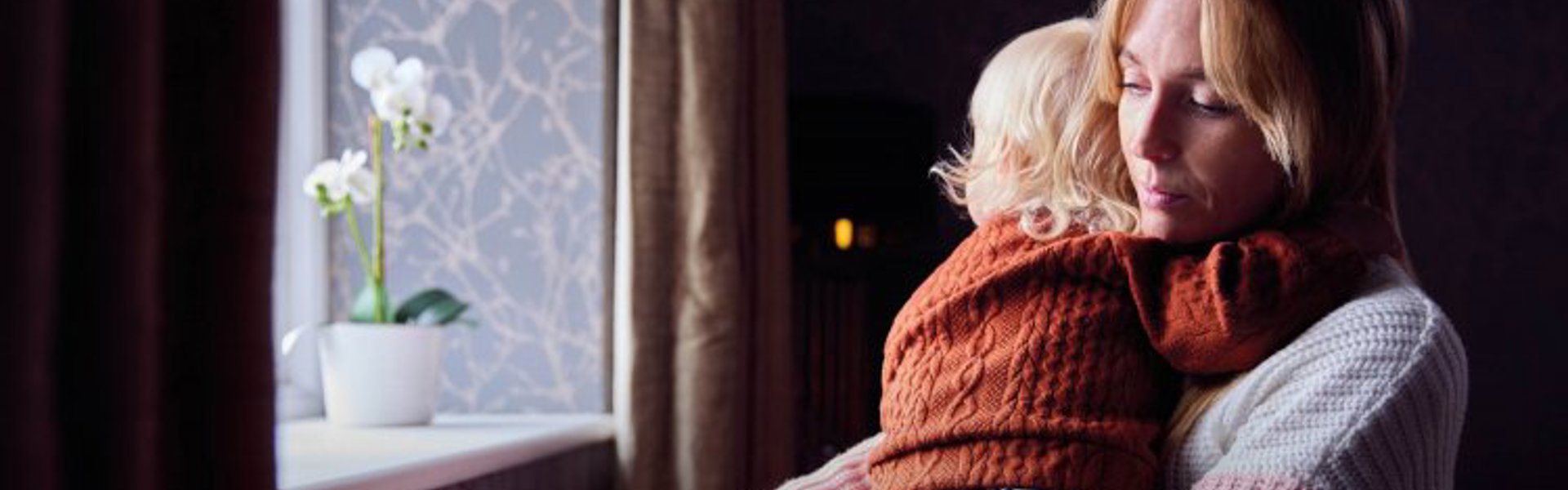 A mother holding her child in a dark room