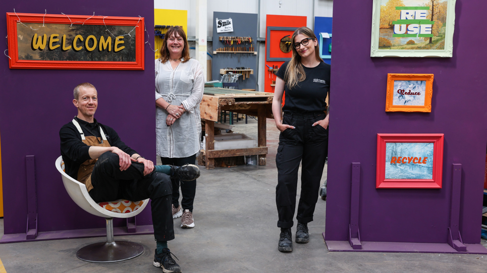 Thirteen colleagues smiling outside the upcycling workshop