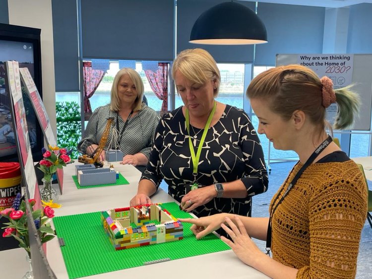 Senior Leadership working with LEGO models of houses at the exhibition