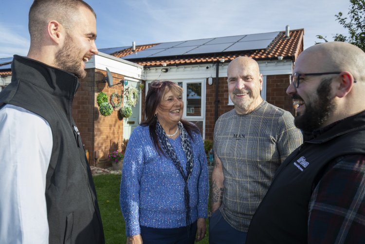 staff members with two customers showing solar panels on a bungalow